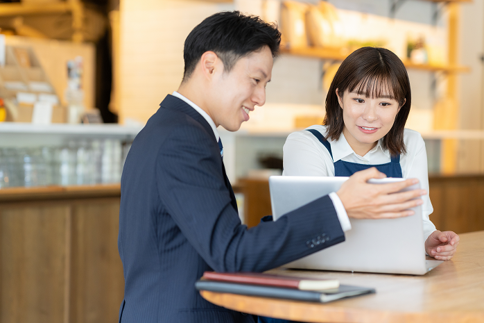 店舗オーナーと打ち合わせをする担当者